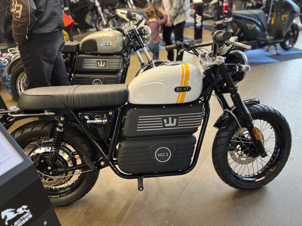 RGNT Scrambler SE auf der Jura-Bike 2023: E-Motorrad mit Retro-Design, weiß-gelbem Tank und schwarzen Akku-Elementen.