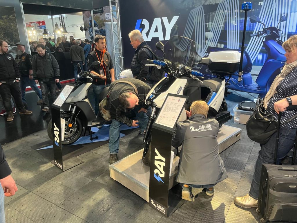 IMOT: Ray E-Roller Modelle in Grau und Weiß, begutachtet von Messebesuchern. Electric Horses.