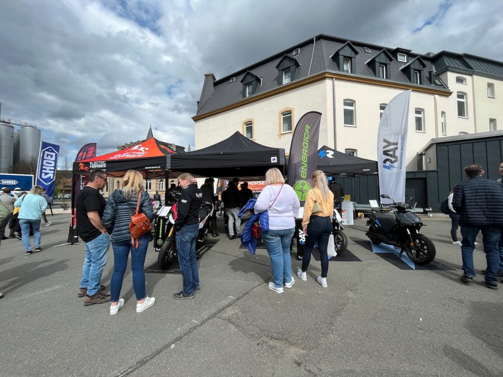 Electric Horses auf Motorradsternfahrt Kulmbach: E-Motorräder und E-Roller unter Pavillons, umgeben von Besuchern.