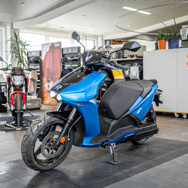 Blauer E-Roller RAY 77 im Verkaufsraum von ELECTRIC HORSES, Wendelstein. Weitere E-Motorräder im Hintergrund.