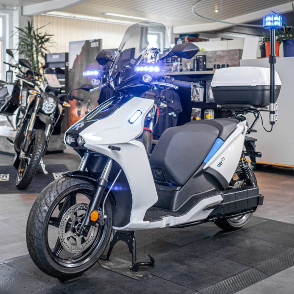 Weisser Elektroroller "Ray 77" von Trinity mit Blaulicht im Verkaufsraum von Electric Horses in Wendelstein.