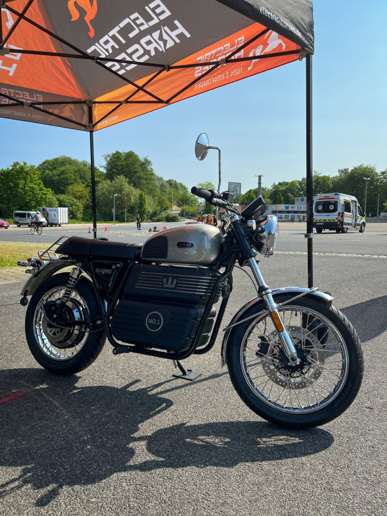 RGNT Classic E-Motorrad auf Verkehrssicherheitstag. Electric Horses Logo im Hintergrund.