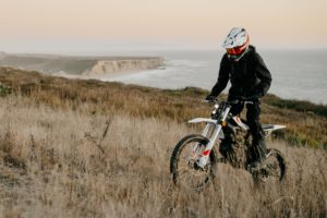 E-Enduro ZERO XE: Fahrer auf Feldweg vor Küste. Elektromotorrad von electric-horses.de.